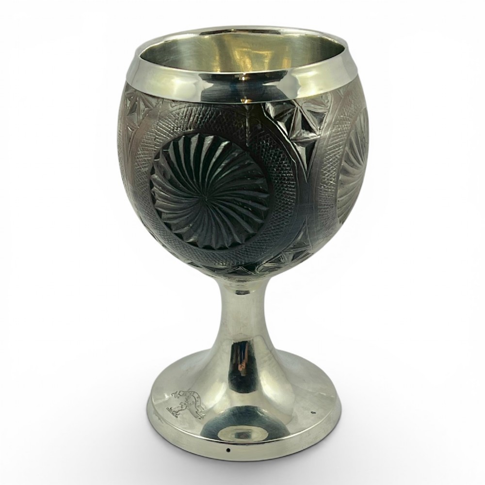 An eighteenth-century carved coconut shell goblet featuring intricate geometric starburst patterns, a silver rim, stem, and hallmarked circular base. View III