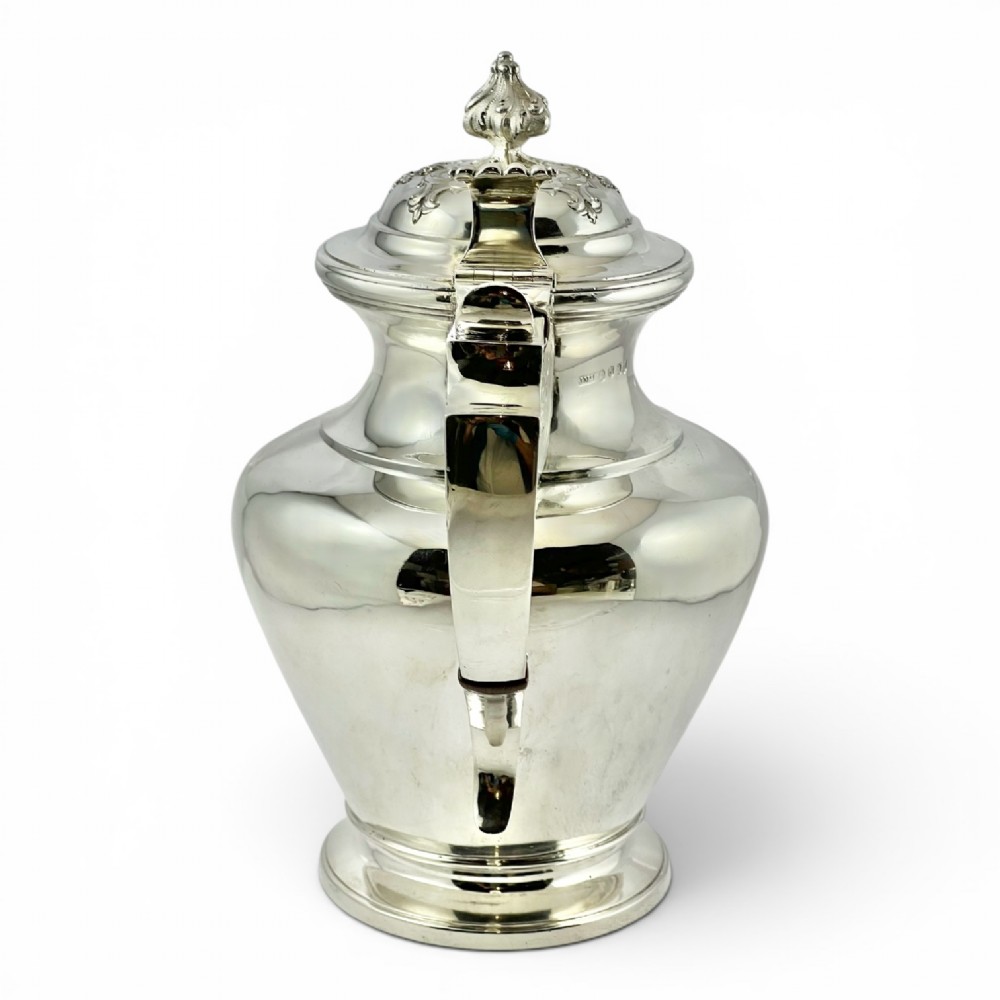 A William IV sterling silver water jug featuring a hinged domed lid, acanthus leaf relief carving, engraved monogram, and an angular insulated handle. View II