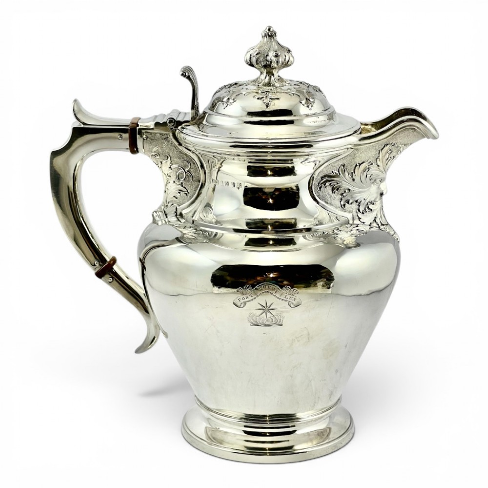 A William IV sterling silver water jug featuring a hinged domed lid, acanthus leaf relief carving, engraved monogram, and an angular insulated handle. View III