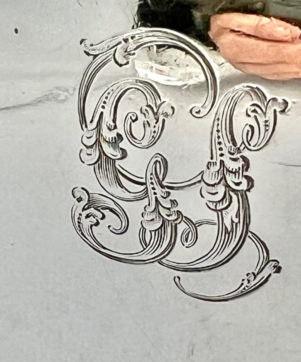 A William IV sterling silver water jug featuring a hinged domed lid, acanthus leaf relief carving, engraved monogram, and an angular insulated handle. View VII