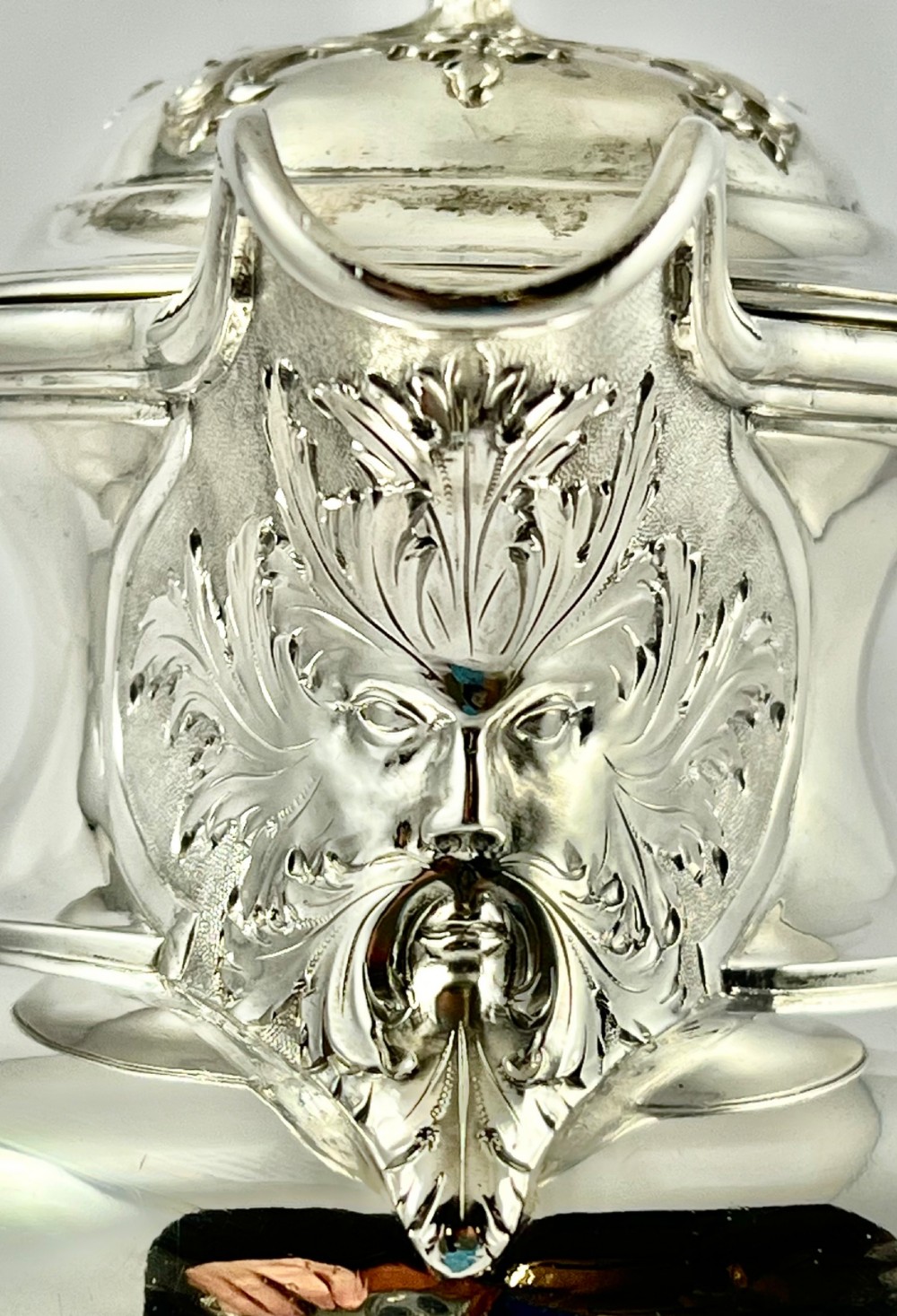 A William IV sterling silver water jug featuring a hinged domed lid, acanthus leaf relief carving, engraved monogram, and an angular insulated handle. View IX