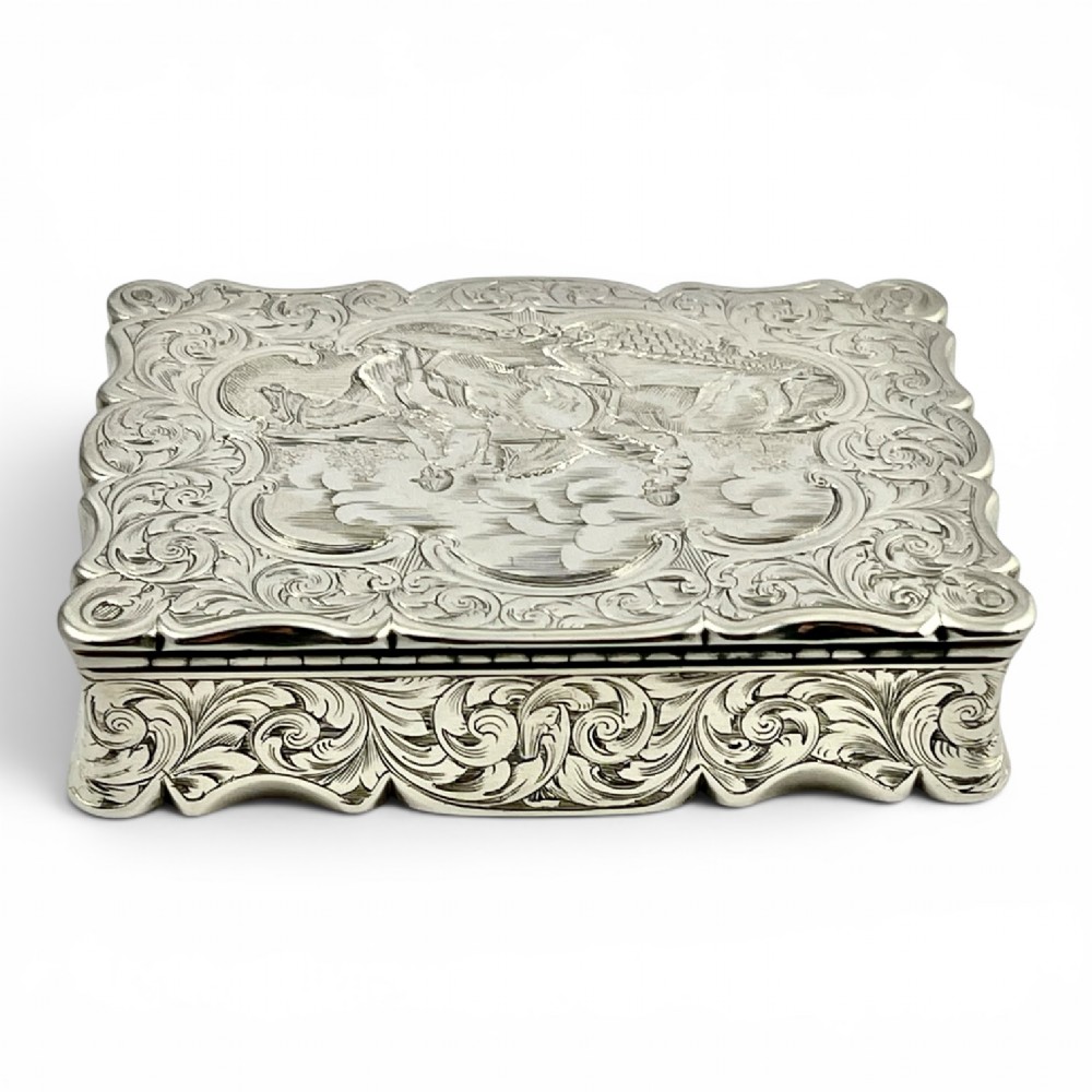 An early Victorian sterling silver table snuff box decorated with elaborate foliate engraving and a central equestrian scene of two jockeys riding horses. View III