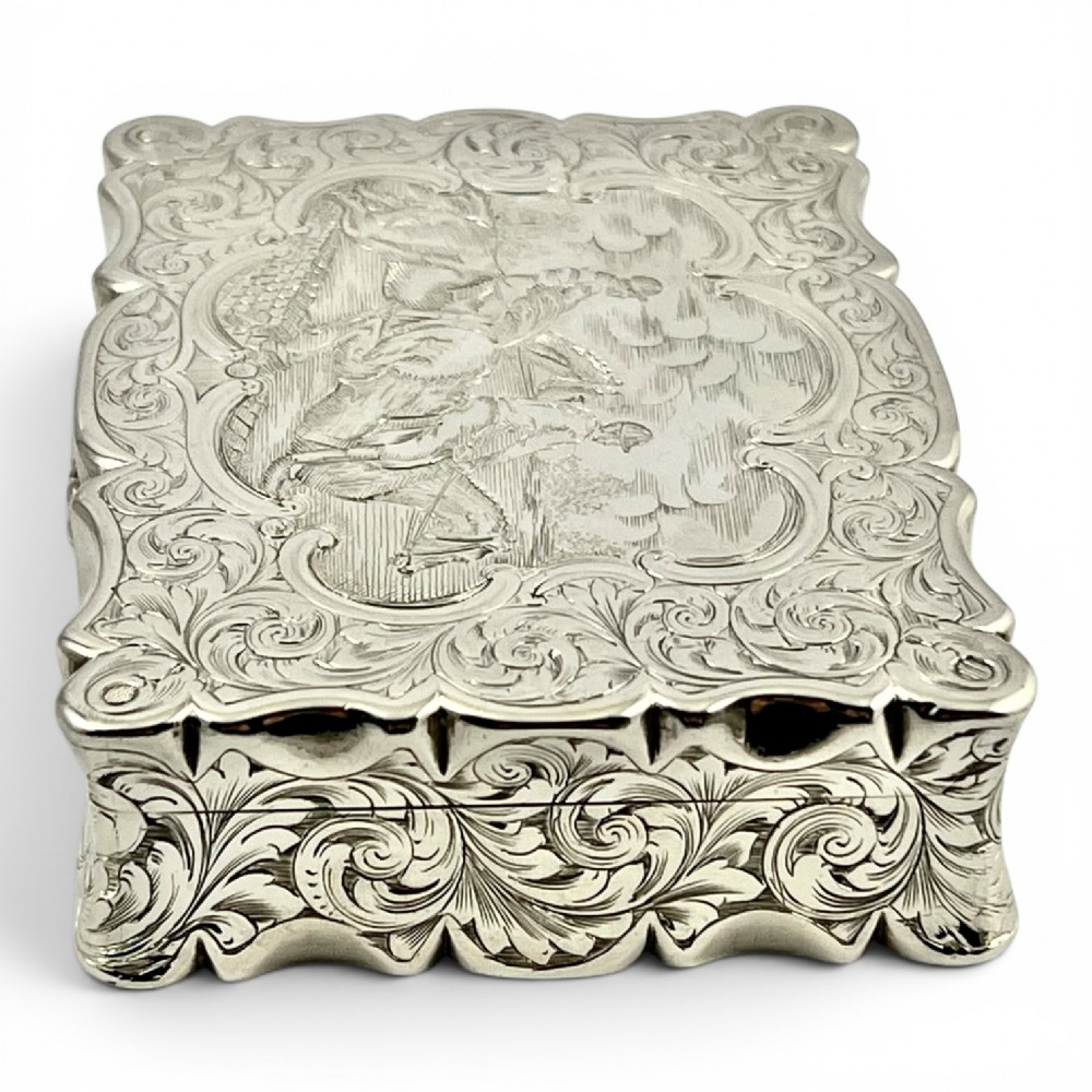An early Victorian sterling silver table snuff box decorated with elaborate foliate engraving and a central equestrian scene of two jockeys riding horses. View IV