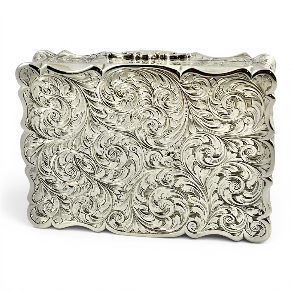 An early Victorian sterling silver table snuff box decorated with elaborate foliate engraving and a central equestrian scene of two jockeys riding horses. View V