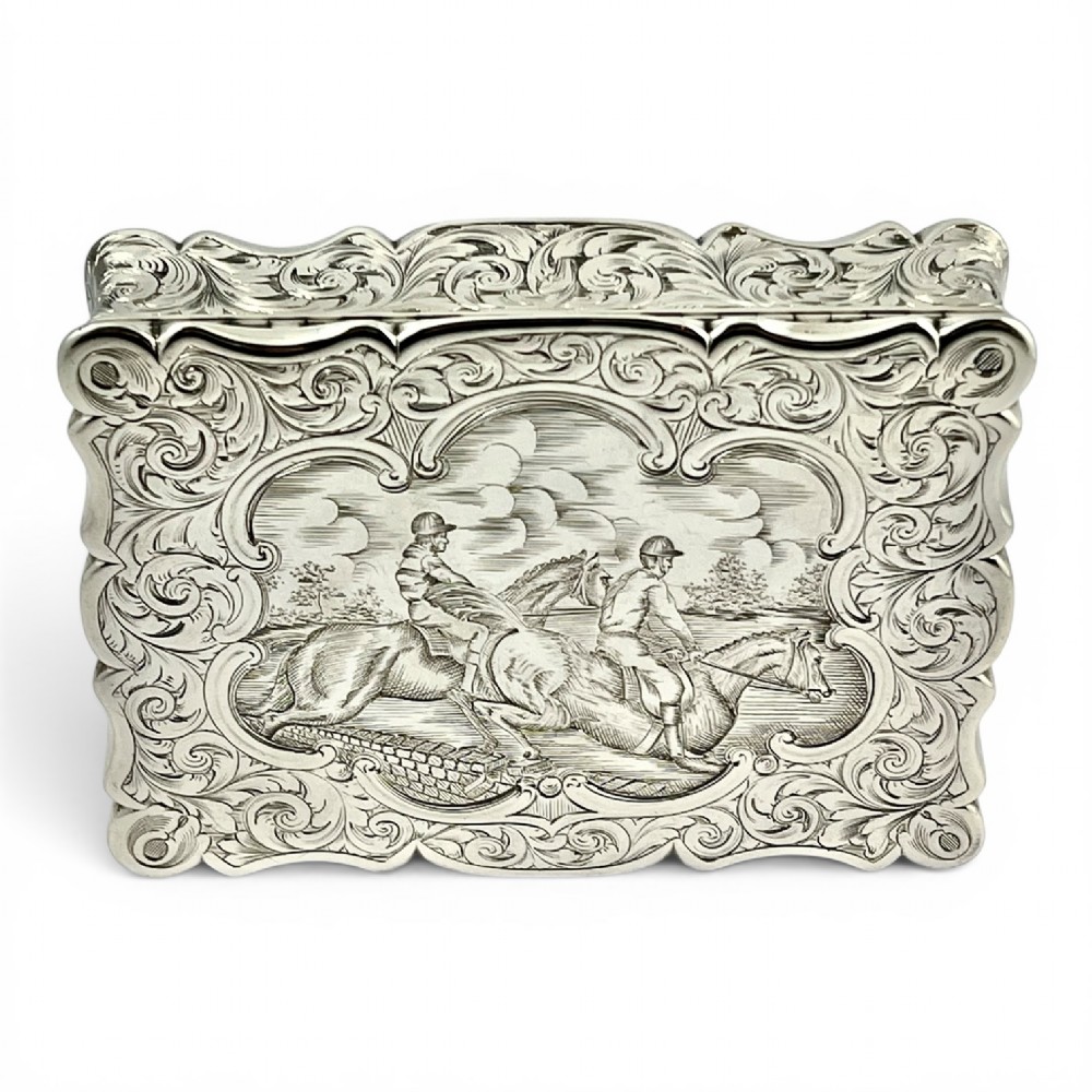 An early Victorian sterling silver table snuff box decorated with elaborate foliate engraving and a central equestrian scene of two jockeys riding horses. View VI