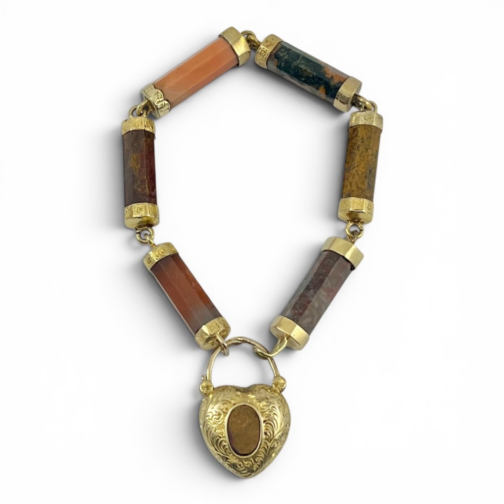 A Victorian 9ct gold bracelet featuring cylindrical faceted agate stone links connected by gold bands and an engraved heart padlock clasp.