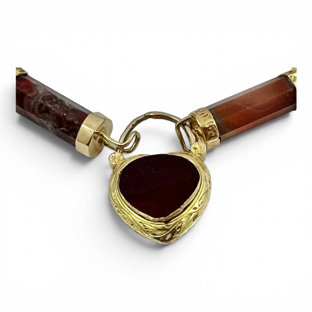 A Victorian 9ct gold bracelet featuring cylindrical faceted agate stone links connected by gold bands and an engraved heart padlock clasp. View IV