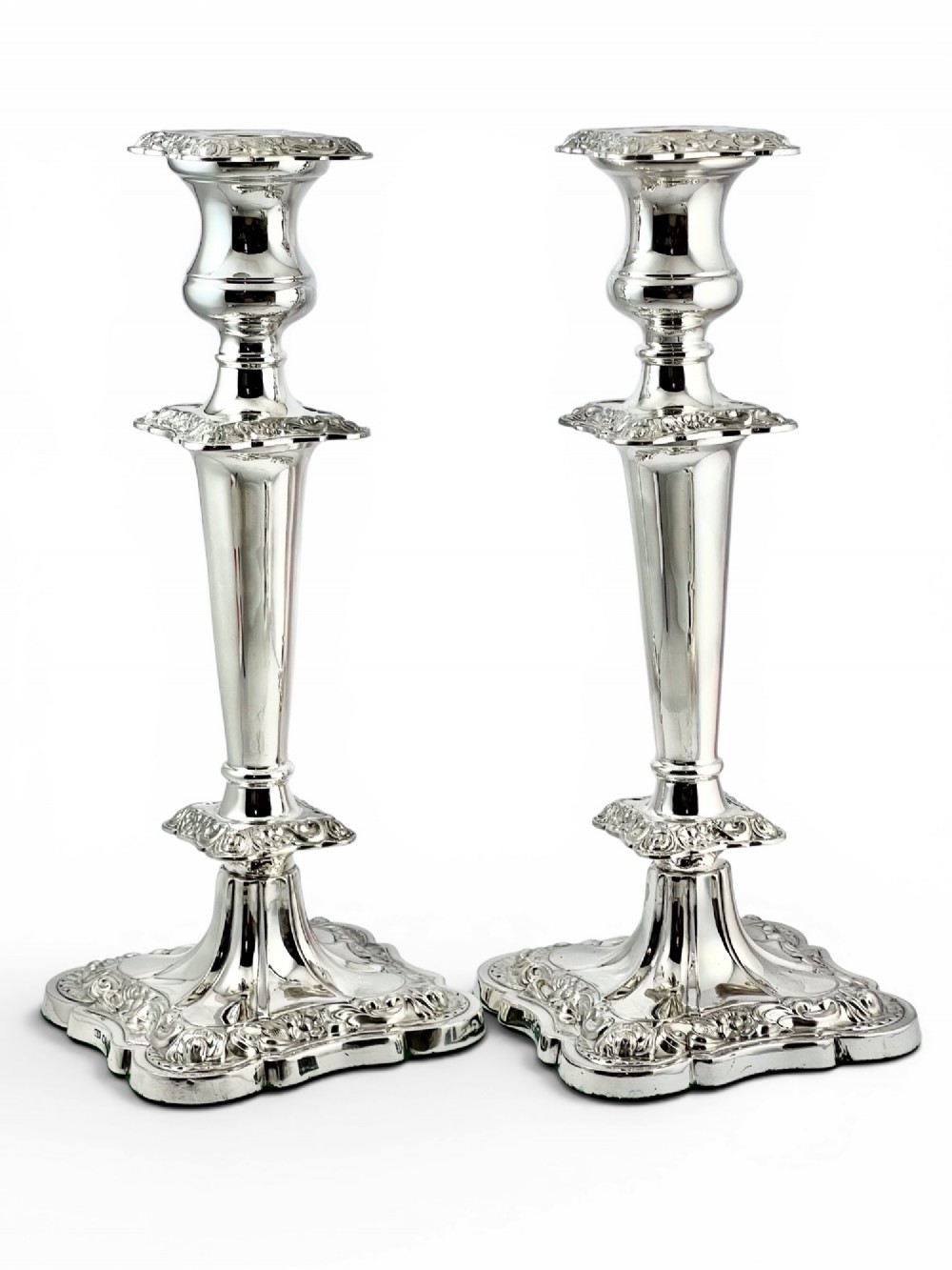 A pair of polished sterling silver candlesticks featuring tapered columns, ornate scroll-patterned square bases, and hallmarked edges. View II