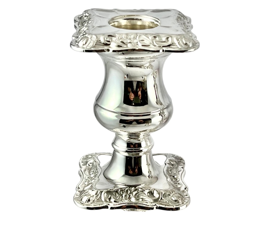 A pair of polished sterling silver candlesticks featuring tapered columns, ornate scroll-patterned square bases, and hallmarked edges. View VI