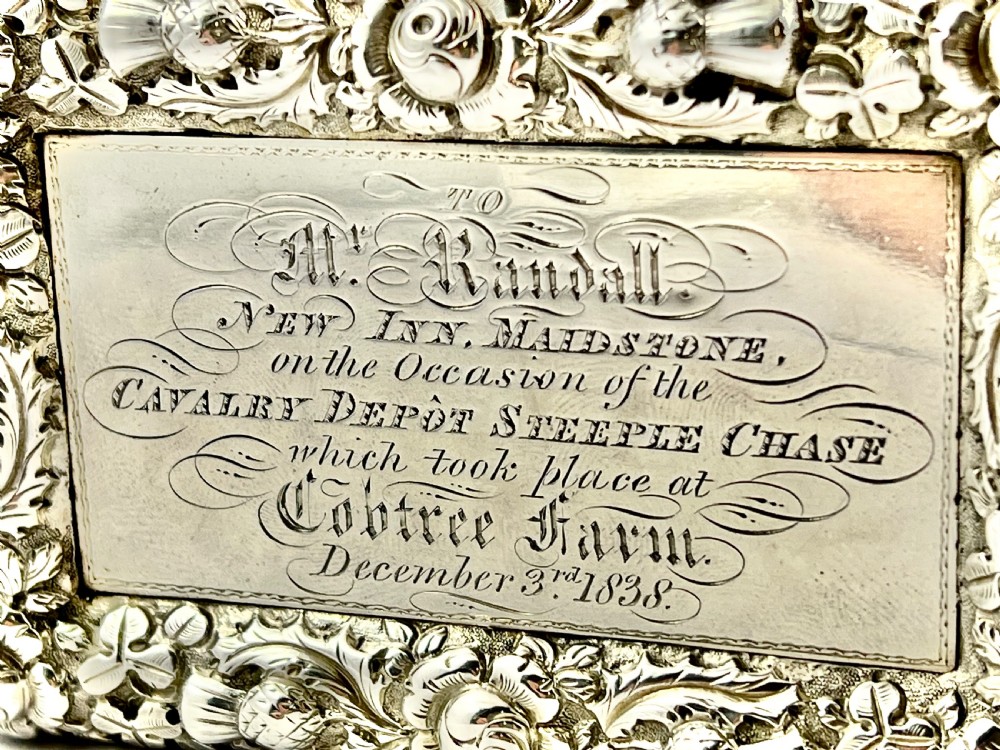 A rectangular Victorian sterling silver snuff box featuring high-relief floral border carving, engine-turned sides, and an engraved inscription on the central lid. View IX