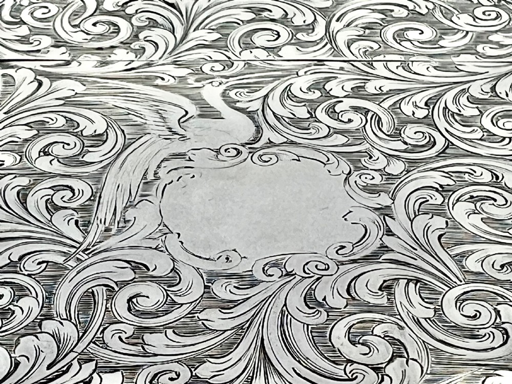 A Victorian sterling silver card case with detailed foliate scrollwork engraving, bird motifs, a blank central cartouche, and a contoured edge. View VIII