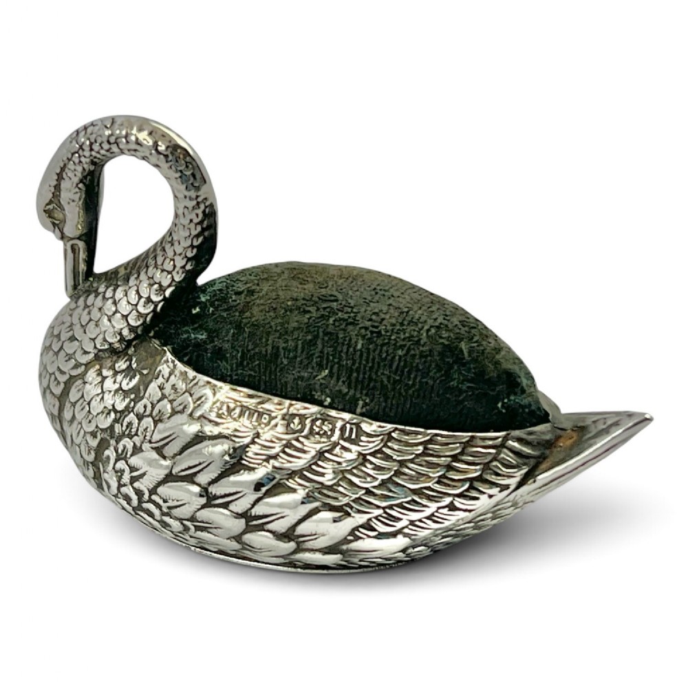 An Edwardian sterling silver pin cushion cast in the form of a swan with a dark green fabric back insert.