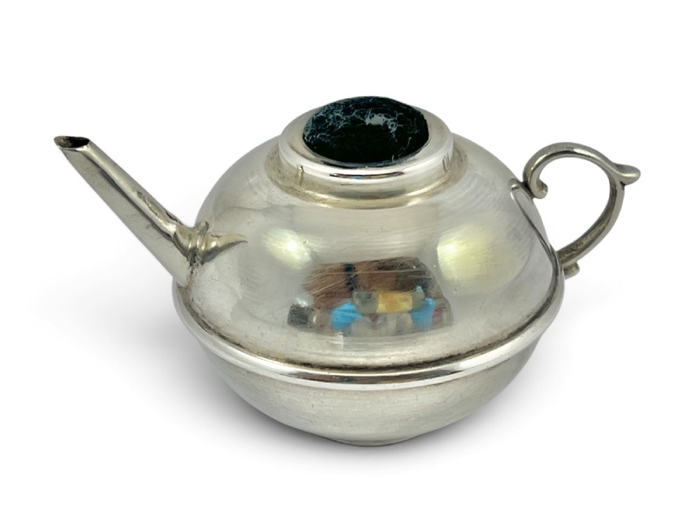 A Victorian sterling silver pin cushion shaped like a miniature teapot with a dark velvet insert at the top opening.