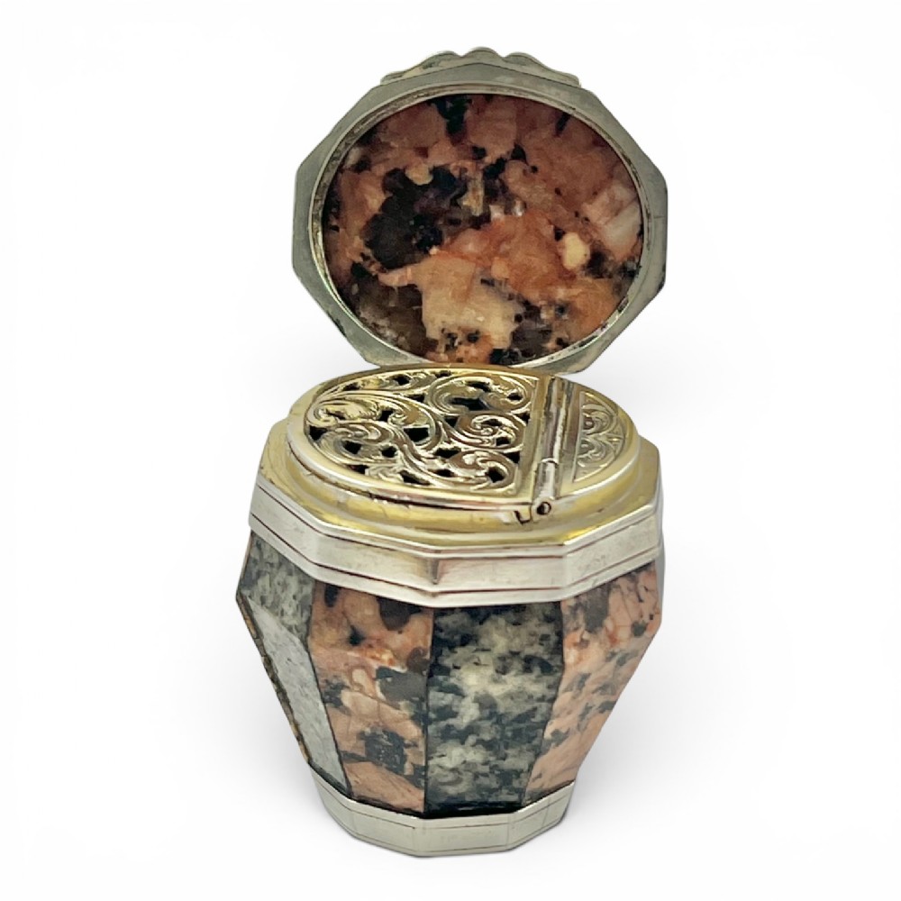 A small Victorian barrel-shaped silver vinaigrette with staves of polished pink and grey granite, shown open to reveal an internal pierced gilt grille.