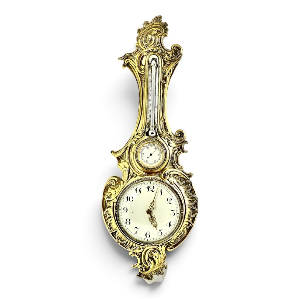 A Victorian silver gilt combination barometer, thermometer, and wall clock featuring ornate Rococo scrollwork and white enamel dials.