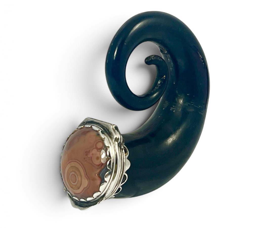 A Victorian Scottish dark horn snuff mull featuring a curled form and a silver-mounted lid set with a circular polished agate stone.