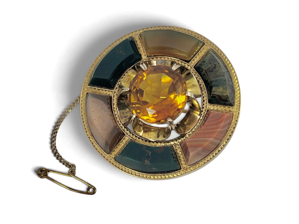 A circular Victorian 18ct gold brooch set with a central faceted yellow citrine gemstone surrounded by wedge-shaped inlaid agate and bloodstone panels, fitted with a safety chain. View II