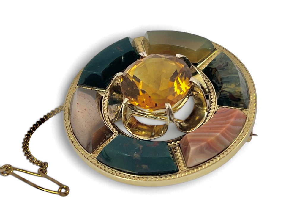 A circular Victorian 18ct gold brooch set with a central faceted yellow citrine gemstone surrounded by wedge-shaped inlaid agate and bloodstone panels, fitted with a safety chain. View III