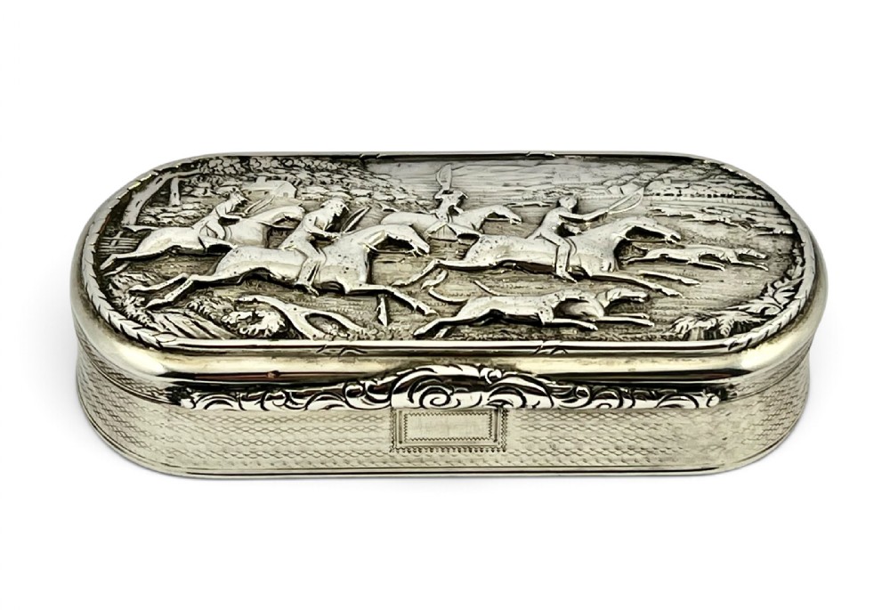 A George IV sterling silver table snuff box with an embossed fox hunting scene on the lid and engine-turned patterning on the sides.