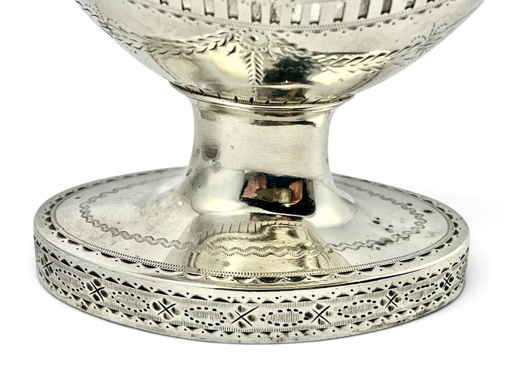 A George III sterling silver sugar basket featuring pierced geometric engraving, a beaded swing handle, a pedestal base, and a fitted cobalt blue glass liner. View IX