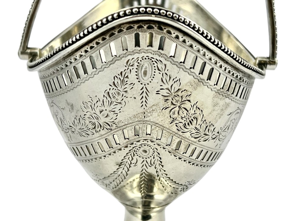 A George III sterling silver sugar basket featuring pierced geometric engraving, a beaded swing handle, a pedestal base, and a fitted cobalt blue glass liner. View XI