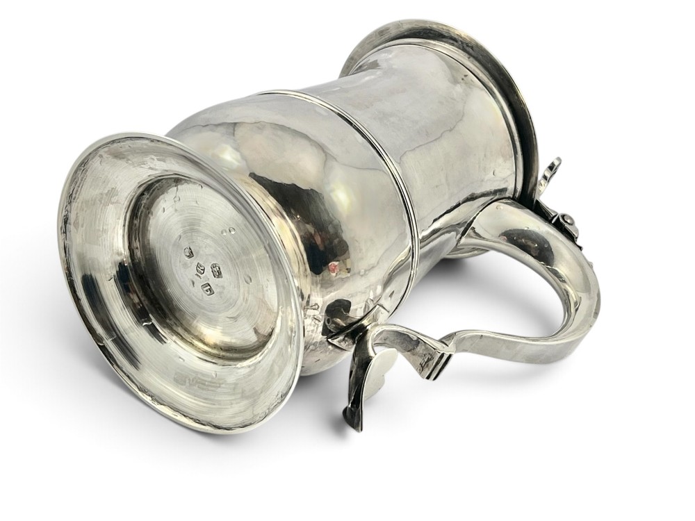 A George III sterling silver lidded tankard featuring a tapered body with a central mid-rib, a hinged domed lid, a pierced thumbpiece, and a double-scroll handle. View II
