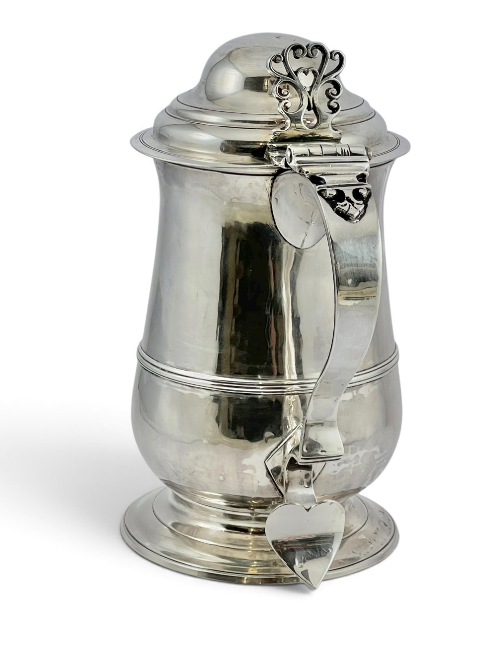 A George III sterling silver lidded tankard featuring a tapered body with a central mid-rib, a hinged domed lid, a pierced thumbpiece, and a double-scroll handle. View VI