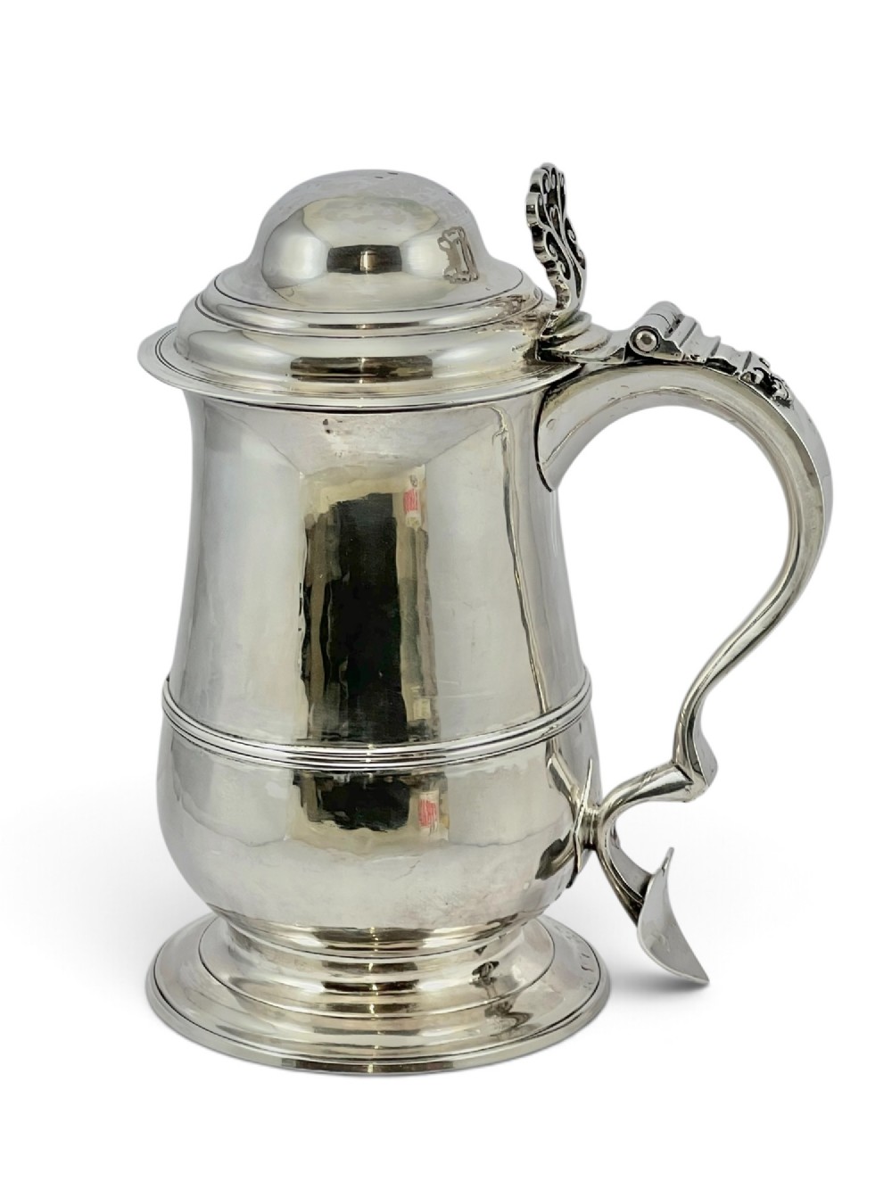 A George III sterling silver lidded tankard featuring a tapered body with a central mid-rib, a hinged domed lid, a pierced thumbpiece, and a double-scroll handle. View IX