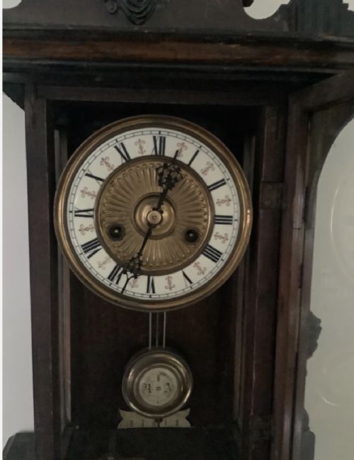 fig 1. A Victorian walnut Vienna wall clock featuring carved finials, architectural columns, a glazed front door, and a white Roman numeral dial with an exposed brass pendulum.