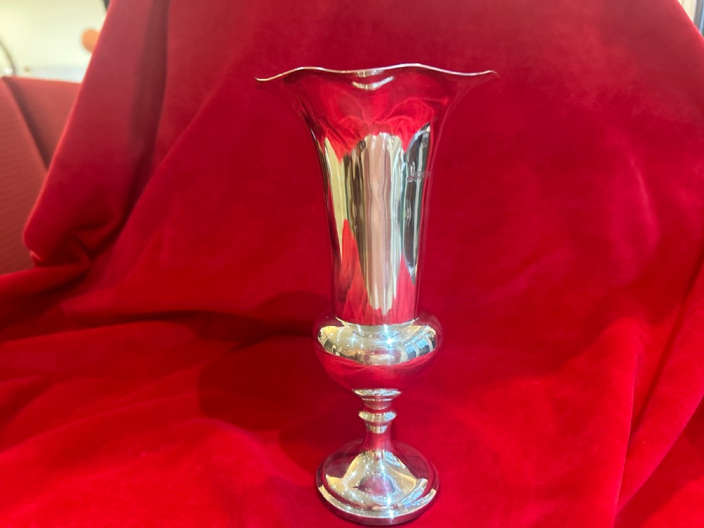 An Edwardian silver trumpet vase with a scalloped flared rim, bulbous lower stem section, and stepped circular pedestal base.