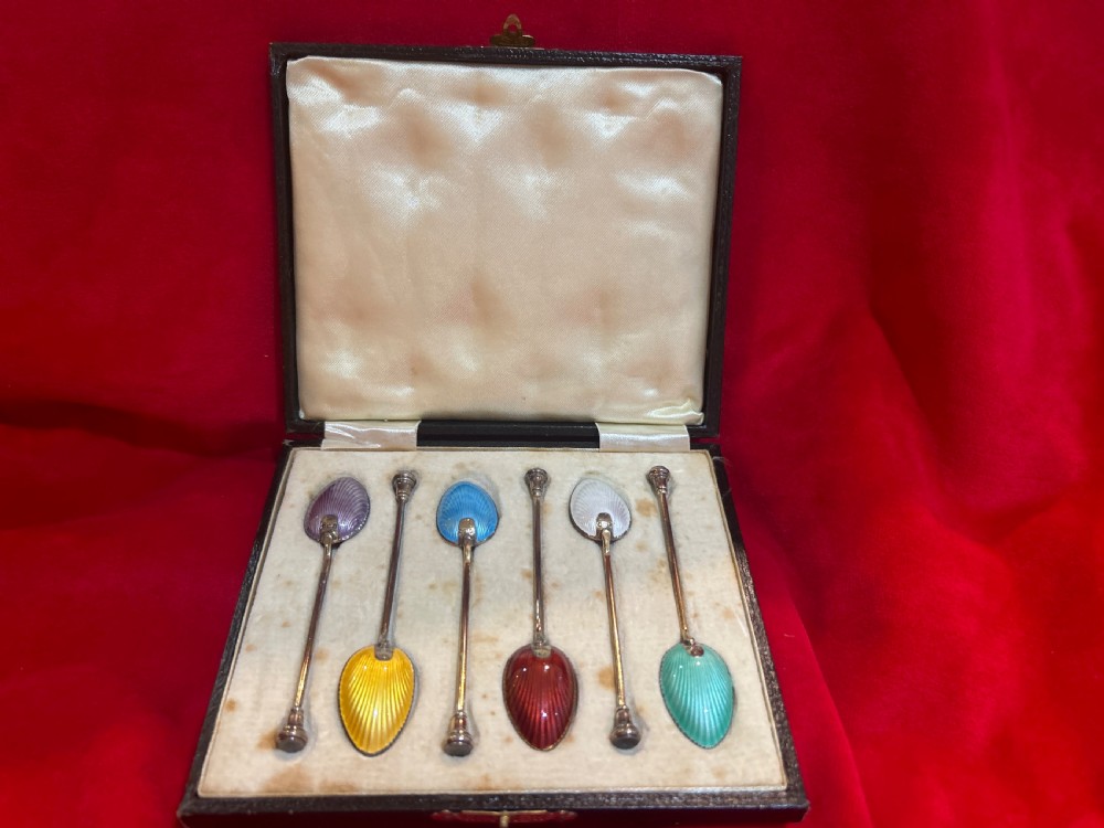 A cased set of six silver spoons featuring vibrant, colourful guilloche enamel bowls housed inside a satin-lined fitted presentation box.