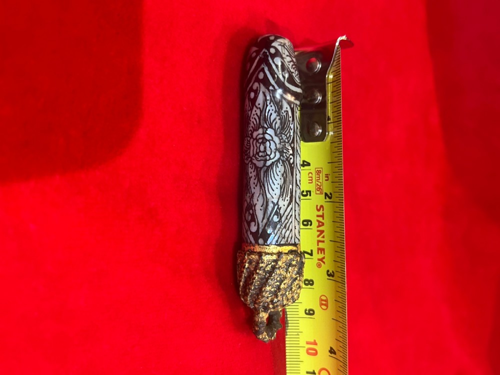 An elongated cylindrical pendant featuring detailed mother of pearl floral inlay with a textured gilded metal suspension loop at one end. View III