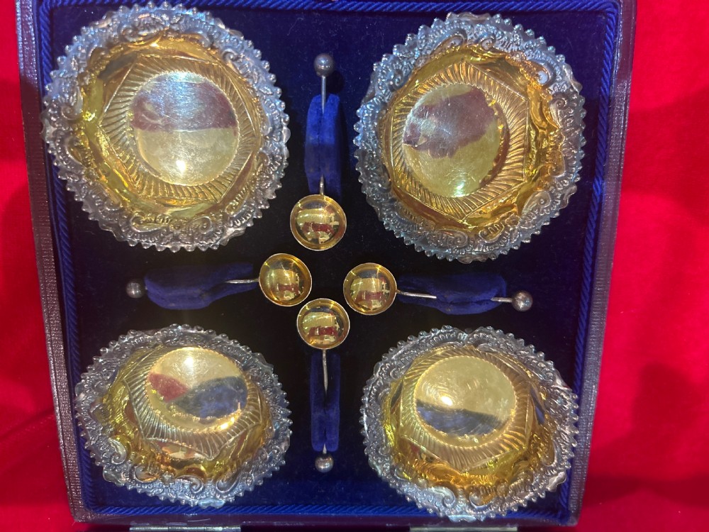 A set of four die-stamped silver open salt cellars with gilt interiors and matching salt spoons, arranged inside a fitted velvet-lined presentation case. View II