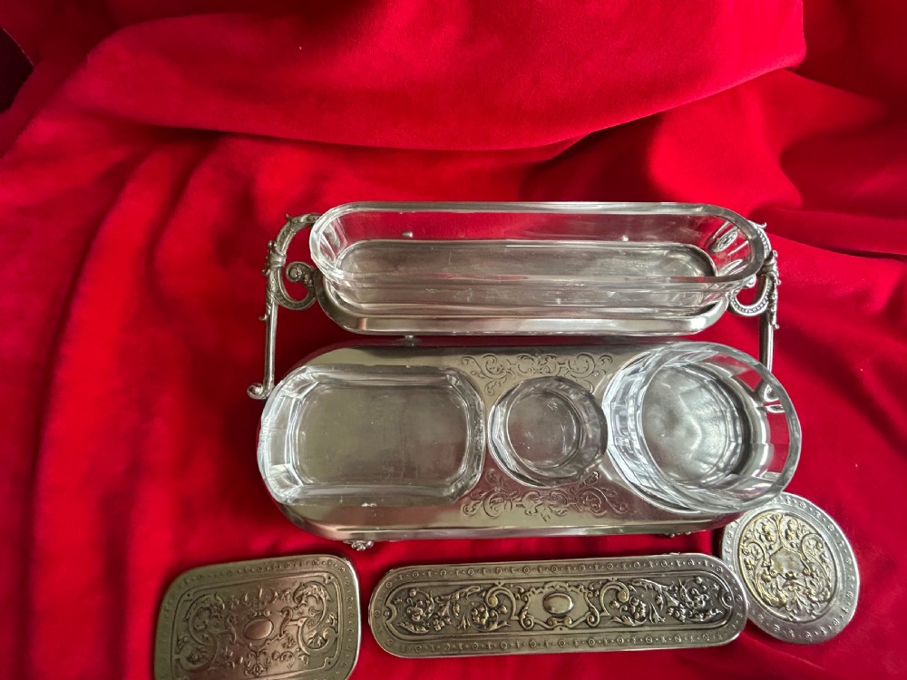 A tiered silver-plated metal stand by WMF holding four clear cut-glass pots with relief-patterned lids resting on ornate feet. View III