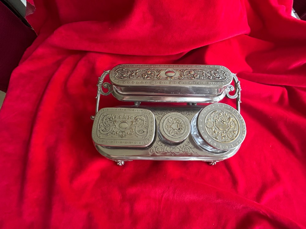 A tiered silver-plated metal stand by WMF holding four clear cut-glass pots with relief-patterned lids resting on ornate feet. View IV