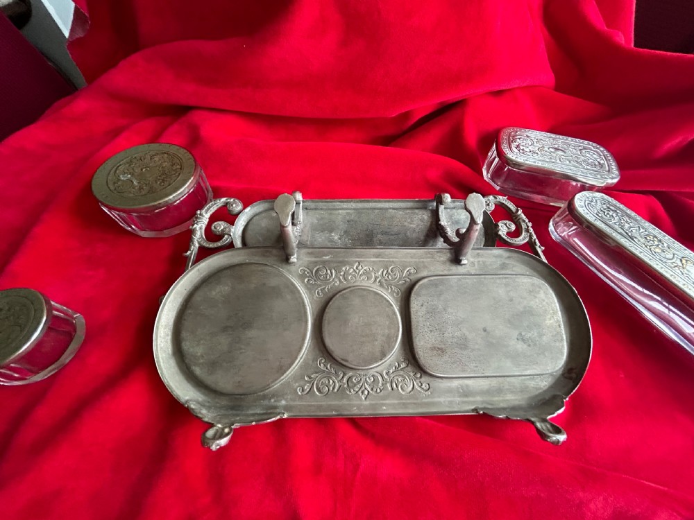 A tiered silver-plated metal stand by WMF holding four clear cut-glass pots with relief-patterned lids resting on ornate feet. View XII