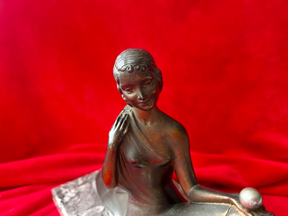 An Art Deco bronze figure group depicting a reclining stylized woman holding an orb beside a seated dog, set on a grey marble plinth. View III
