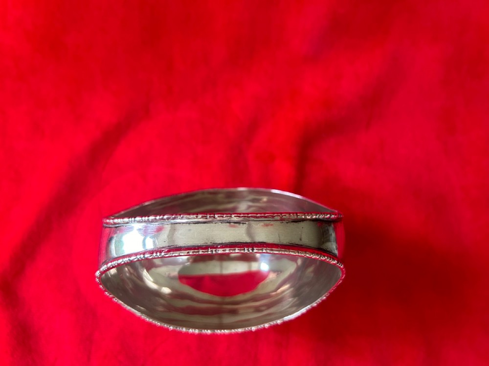 A polished silver bonbon dish with a high overhead handle, beaded rim, and claw feet. View II