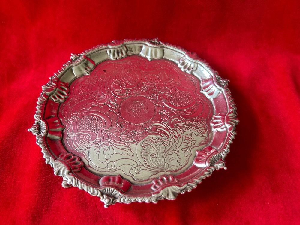 A circular George III sterling silver card tray featuring a shell and scroll cast rim with intricate hand-engraved foliate ornamentation on the flat surface.