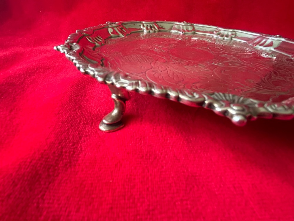 A circular George III sterling silver card tray featuring a shell and scroll cast rim with intricate hand-engraved foliate ornamentation on the flat surface. View II