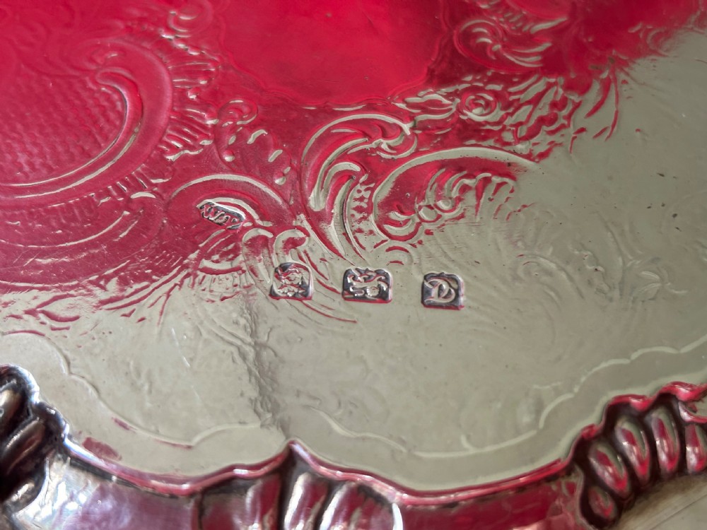 A circular George III sterling silver card tray featuring a shell and scroll cast rim with intricate hand-engraved foliate ornamentation on the flat surface. View V
