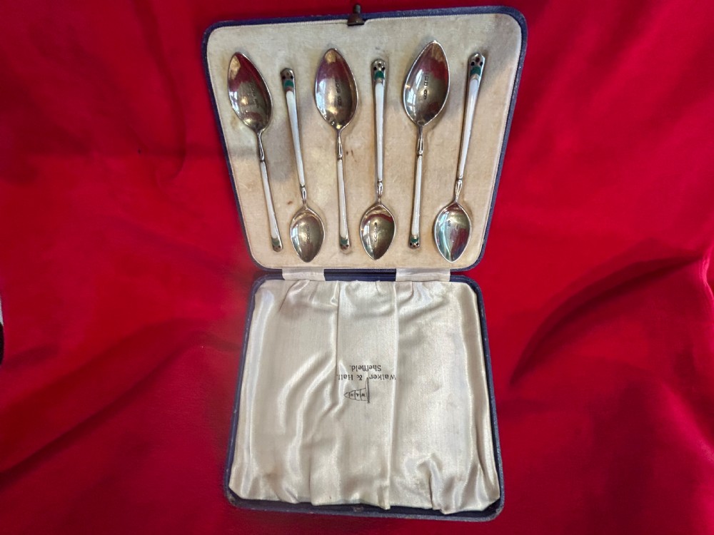 A cased set of six George V sterling silver coffee spoons with white, green, and red enamel decoration in a velvet-lined fitted box. View IV