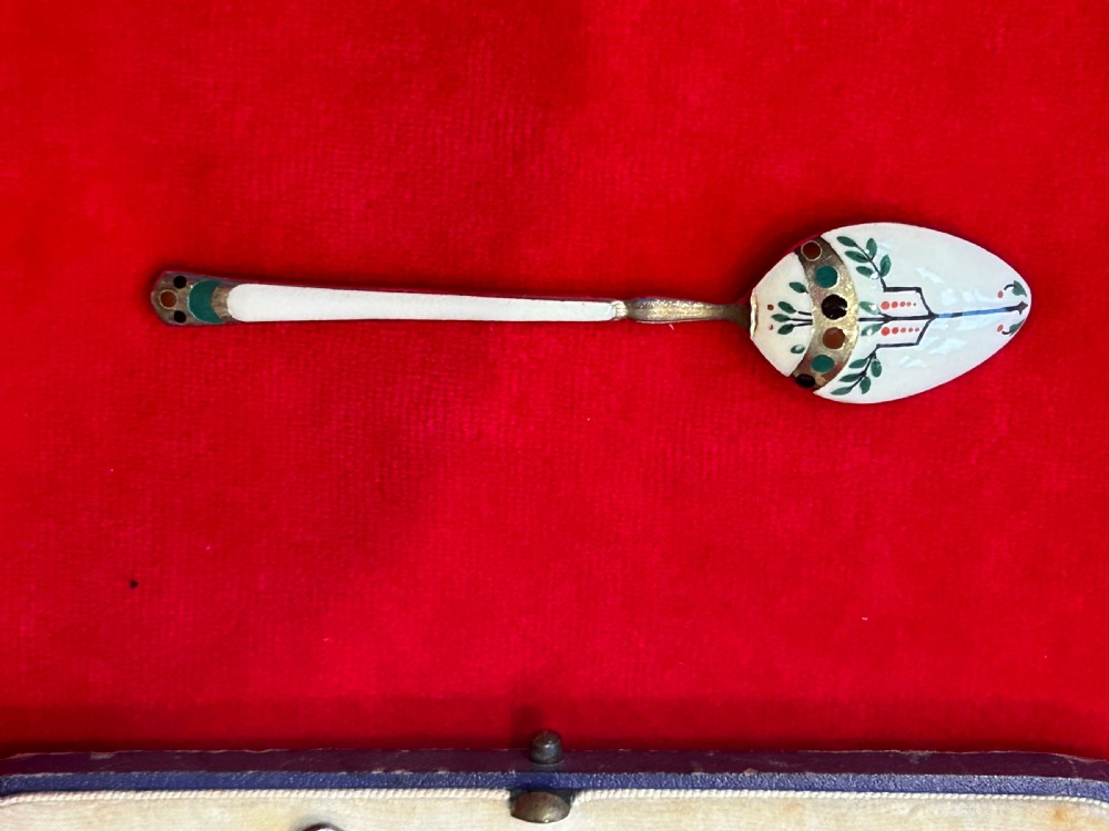 A cased set of six George V sterling silver coffee spoons with white, green, and red enamel decoration in a velvet-lined fitted box. View V