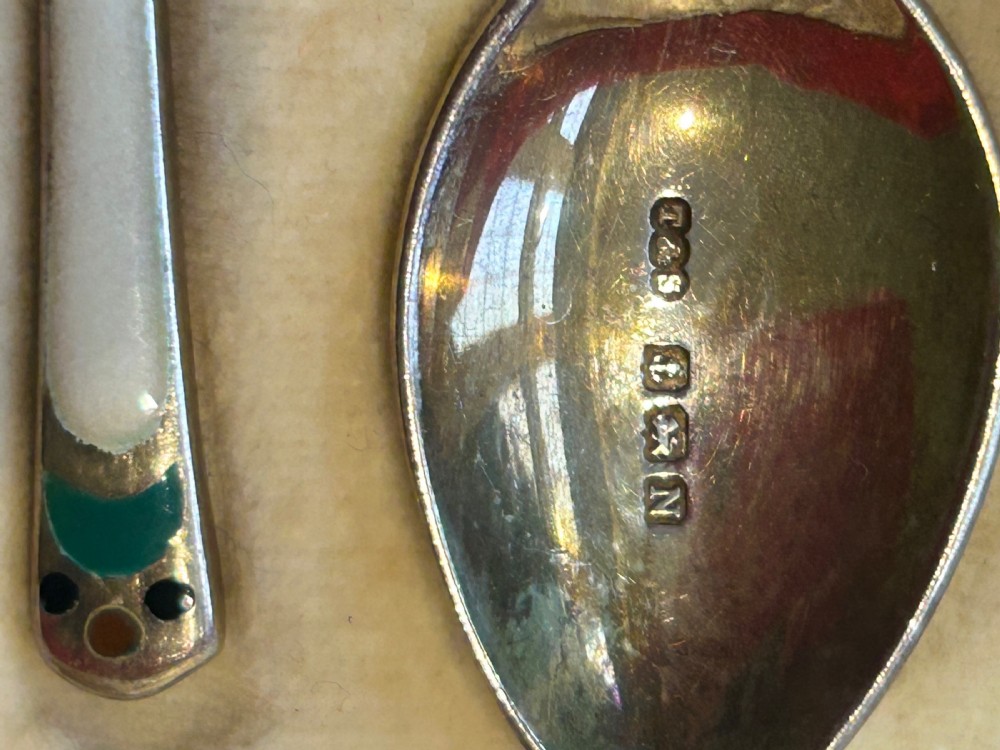 A cased set of six George V sterling silver coffee spoons with white, green, and red enamel decoration in a velvet-lined fitted box. View VI