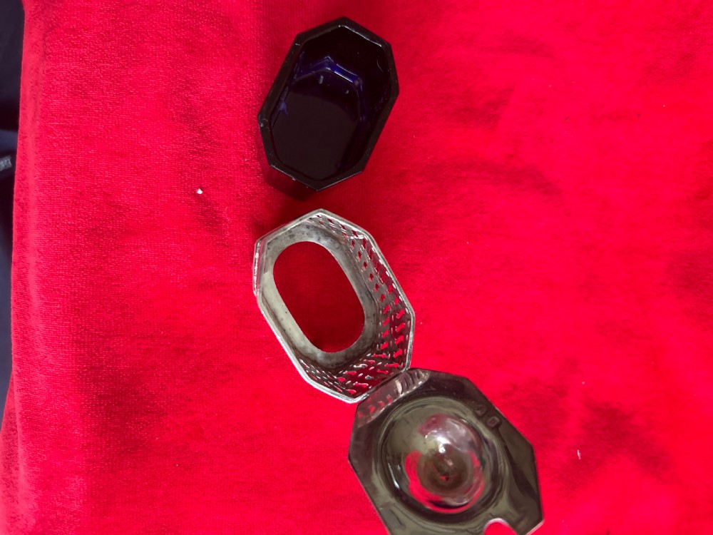 A pierced silver mustard pot featuring a hinged lid with thumbpiece, scroll handle, and small ball feet. View VI