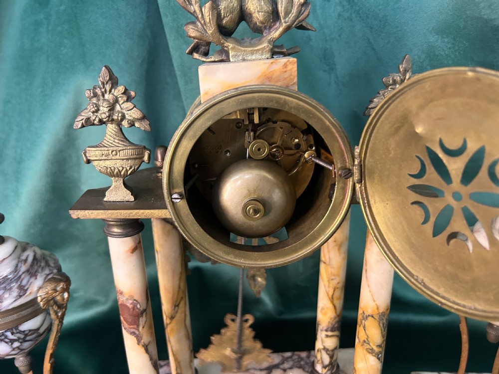 A French late 19th-century clock garniture in veined cream marble and gilt metal featuring a columned clock flanked by two matching cassolette urns. View IV