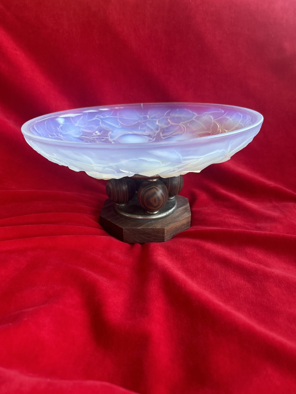 A shallow Art Deco opalescent glass tazza featuring botanical relief patterns, resting on a turned dark wood pedestal base with spherical feet.