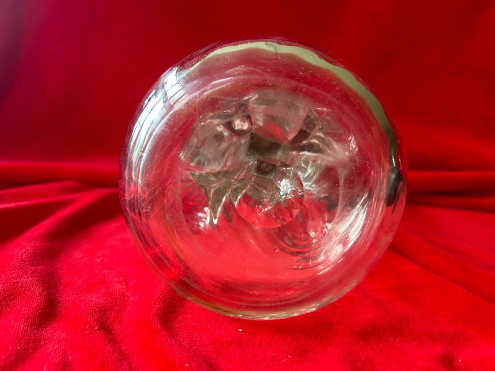 An Edwardian clear glass decanter featuring a pinched waist, decorative pierced silver overlay around the shoulder, and an ornate silver stopper. View V