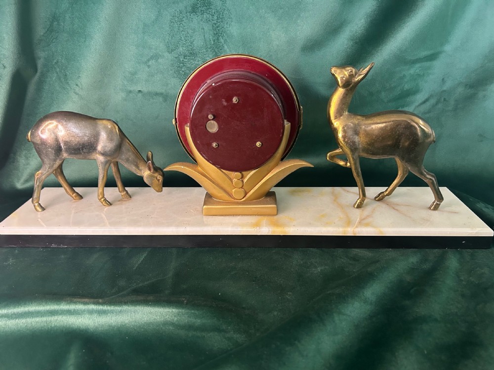 An Art Deco circular brass clock signed Silvoz Paris featuring Arabic numerals on a gold-toned face mounted on a rectangular base. View VI