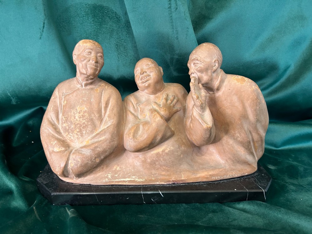 An Art Deco terracotta sculpture depicting three expressive figures mounted on a black marble base.
